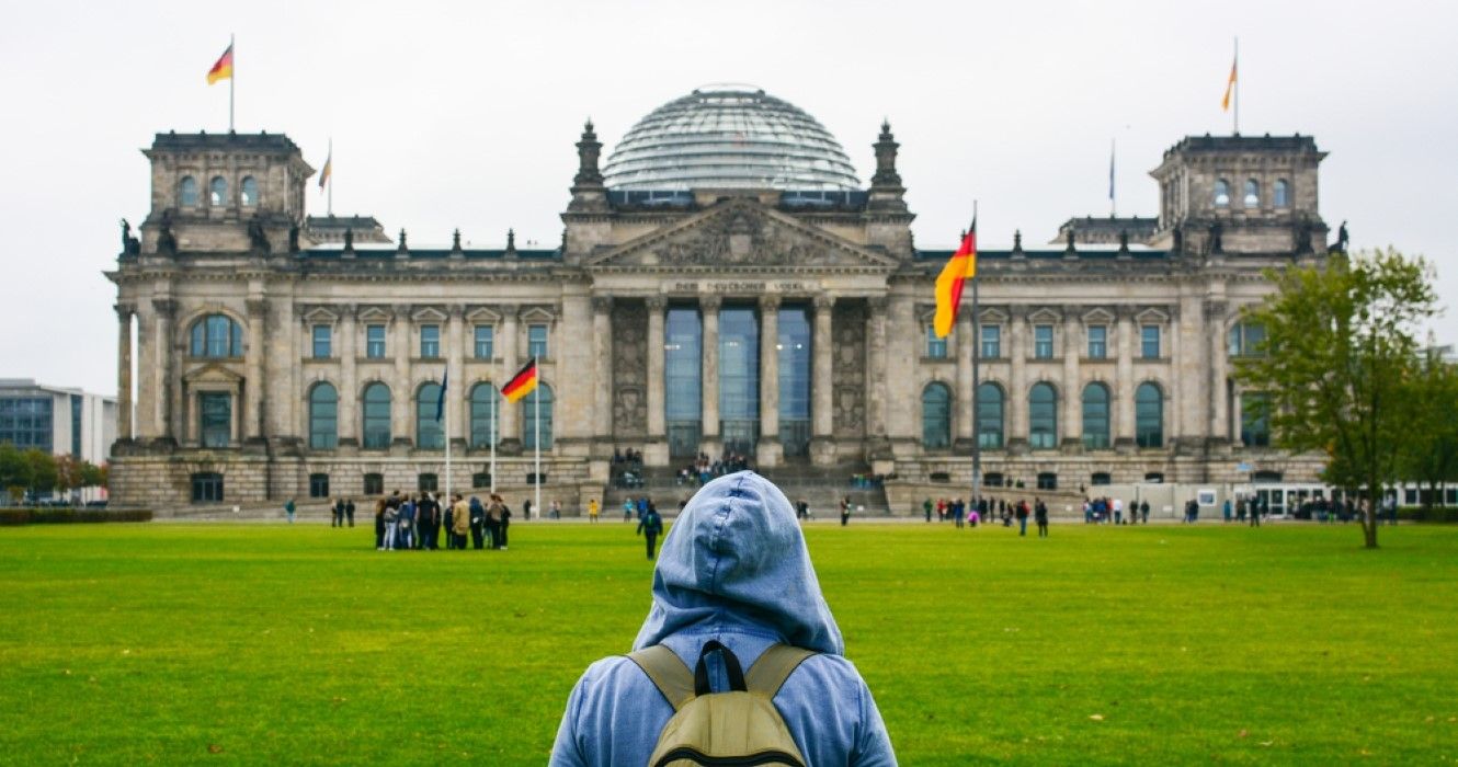 Person with backpack looking at Bundestag building in Berlin, Germany