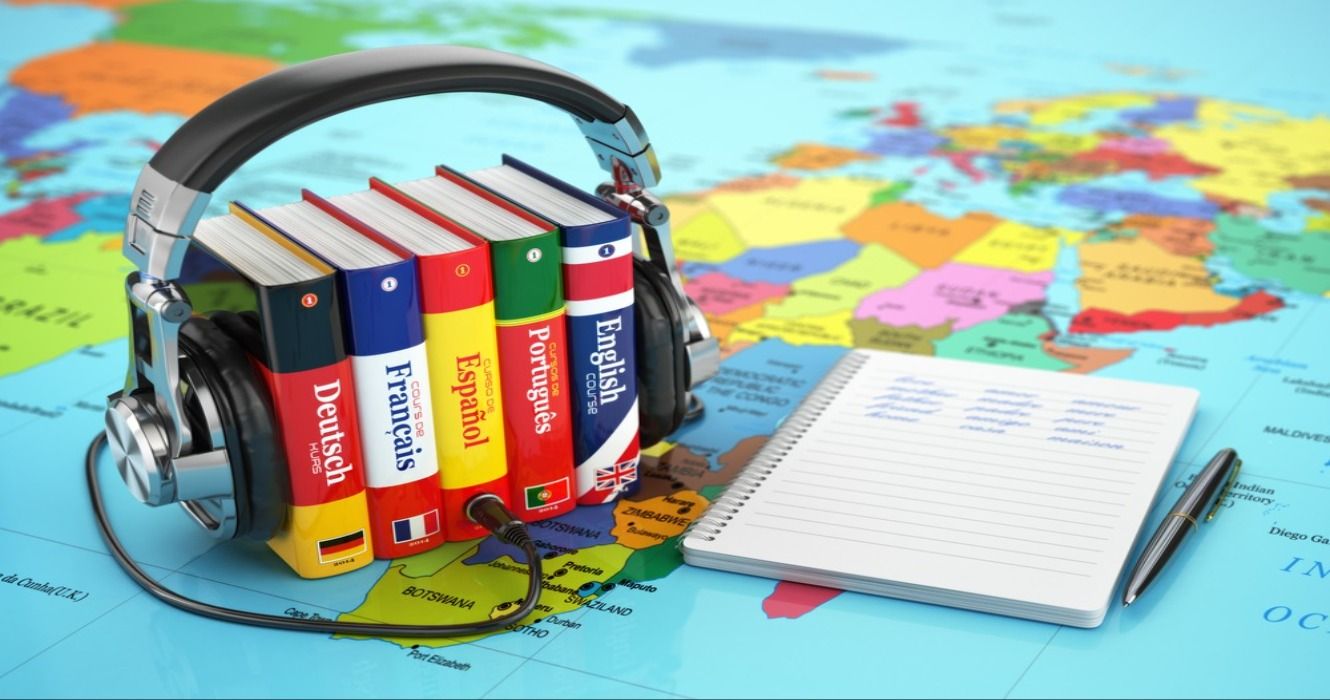 Foreign language dictionaries, headphones, and a note pad with a pen on a world map
