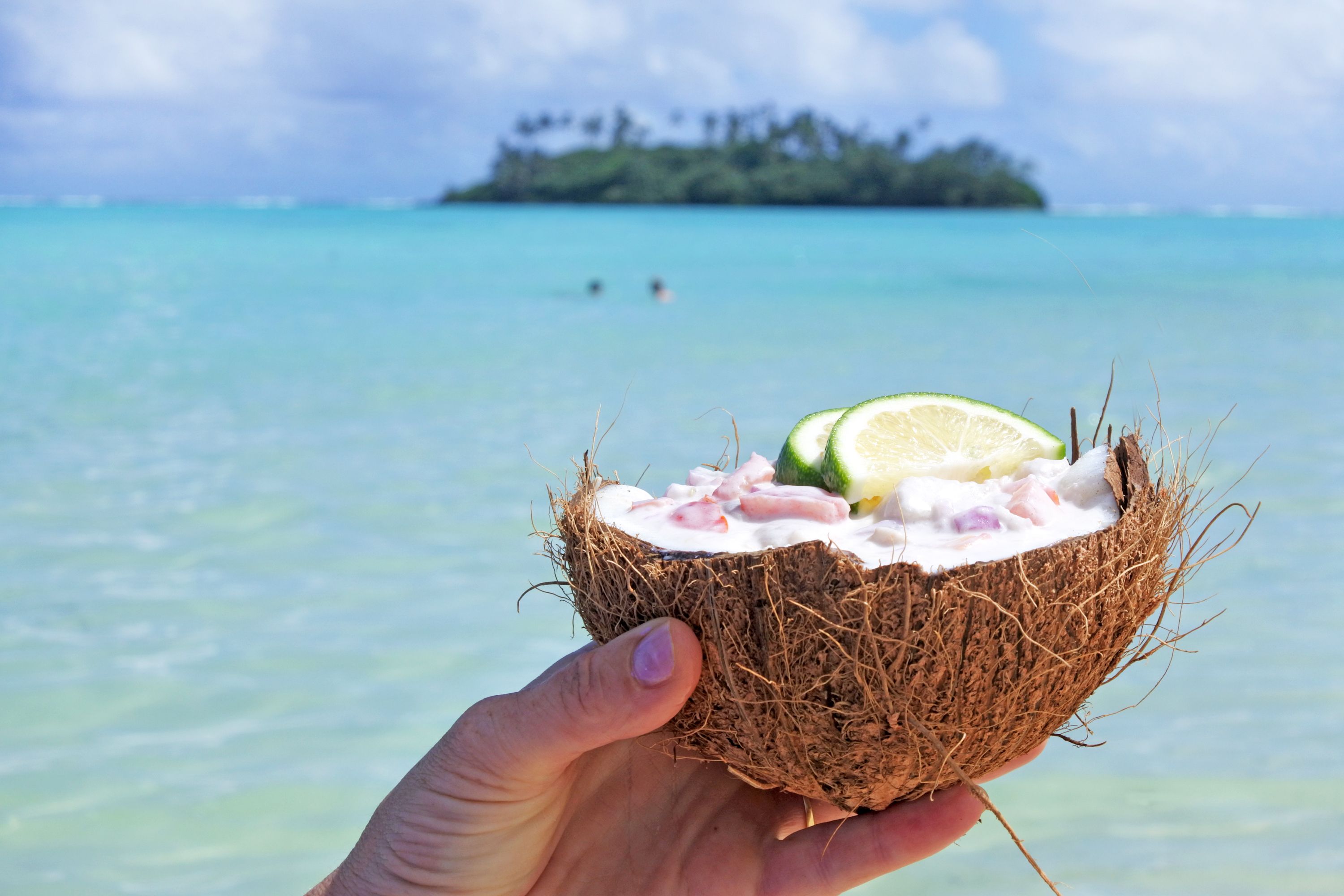 Woman hand holding a coconut by the ocean 