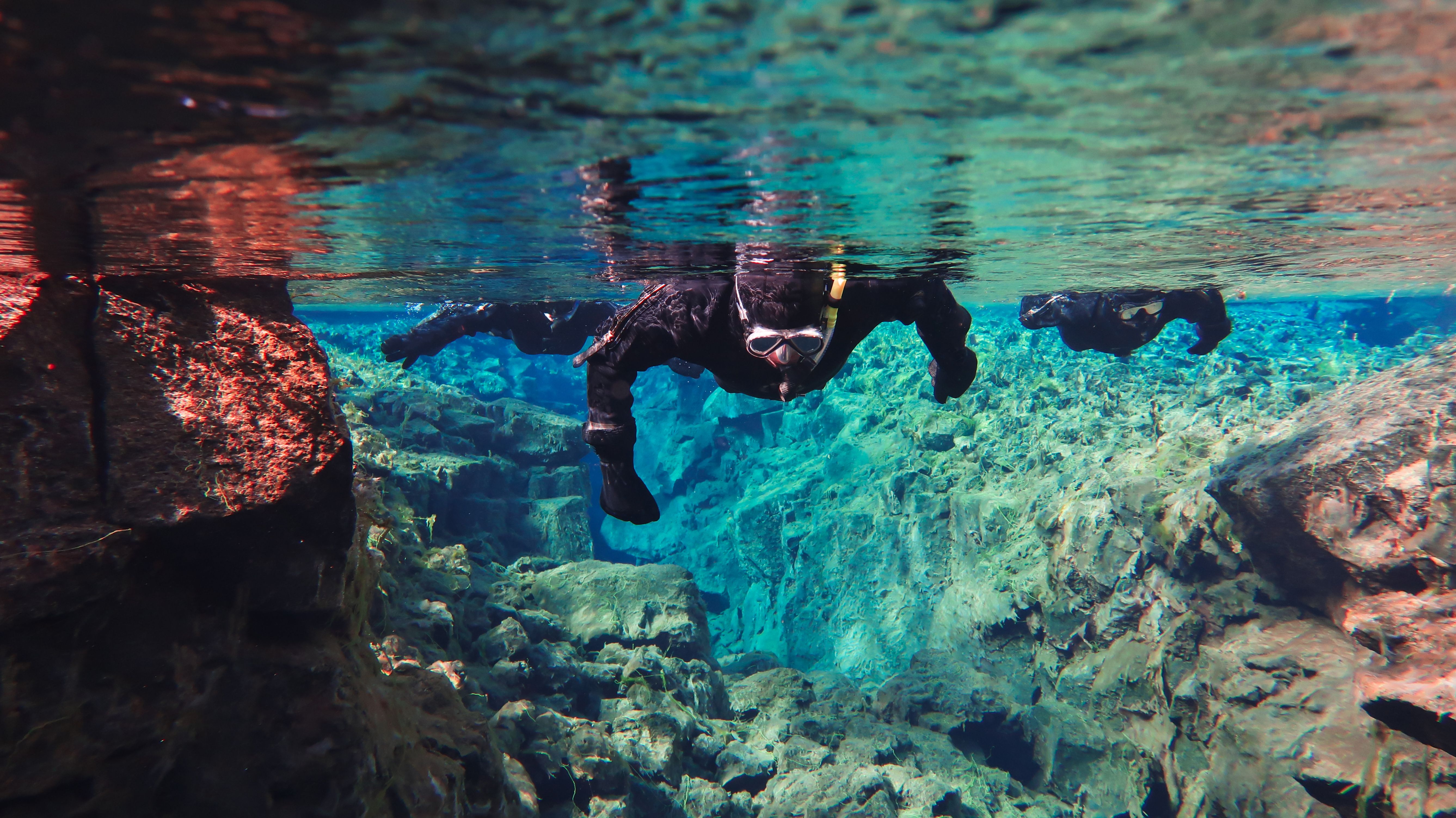 Person in drysuit snorkeling in blue water 