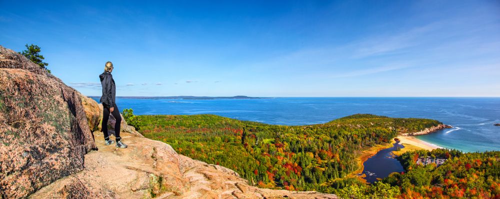 A hiker on the Beehive Trail in Acadia National Park during the fall, Maine, USA
