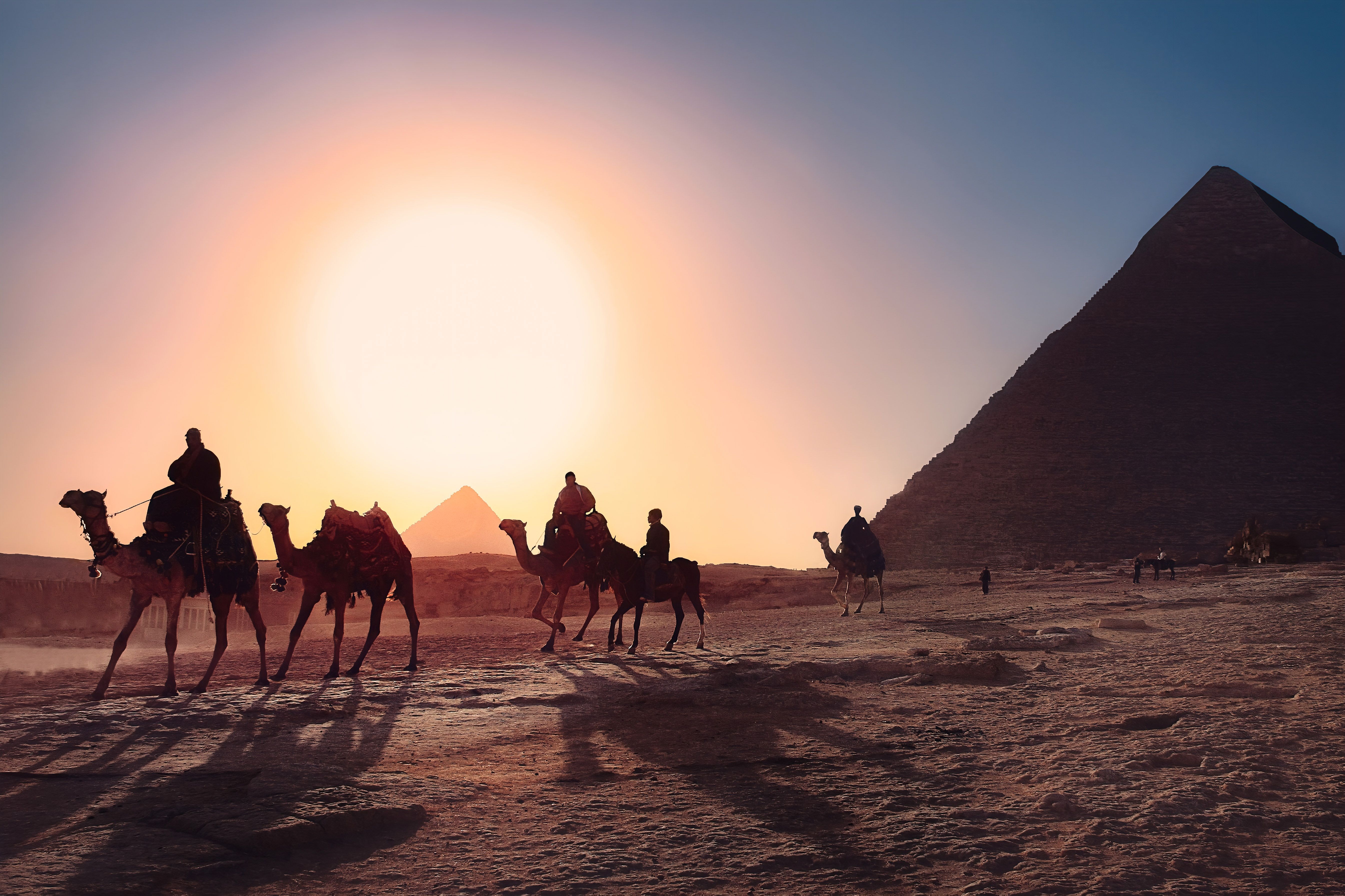 Group riding camels by the pyramids of Egypt