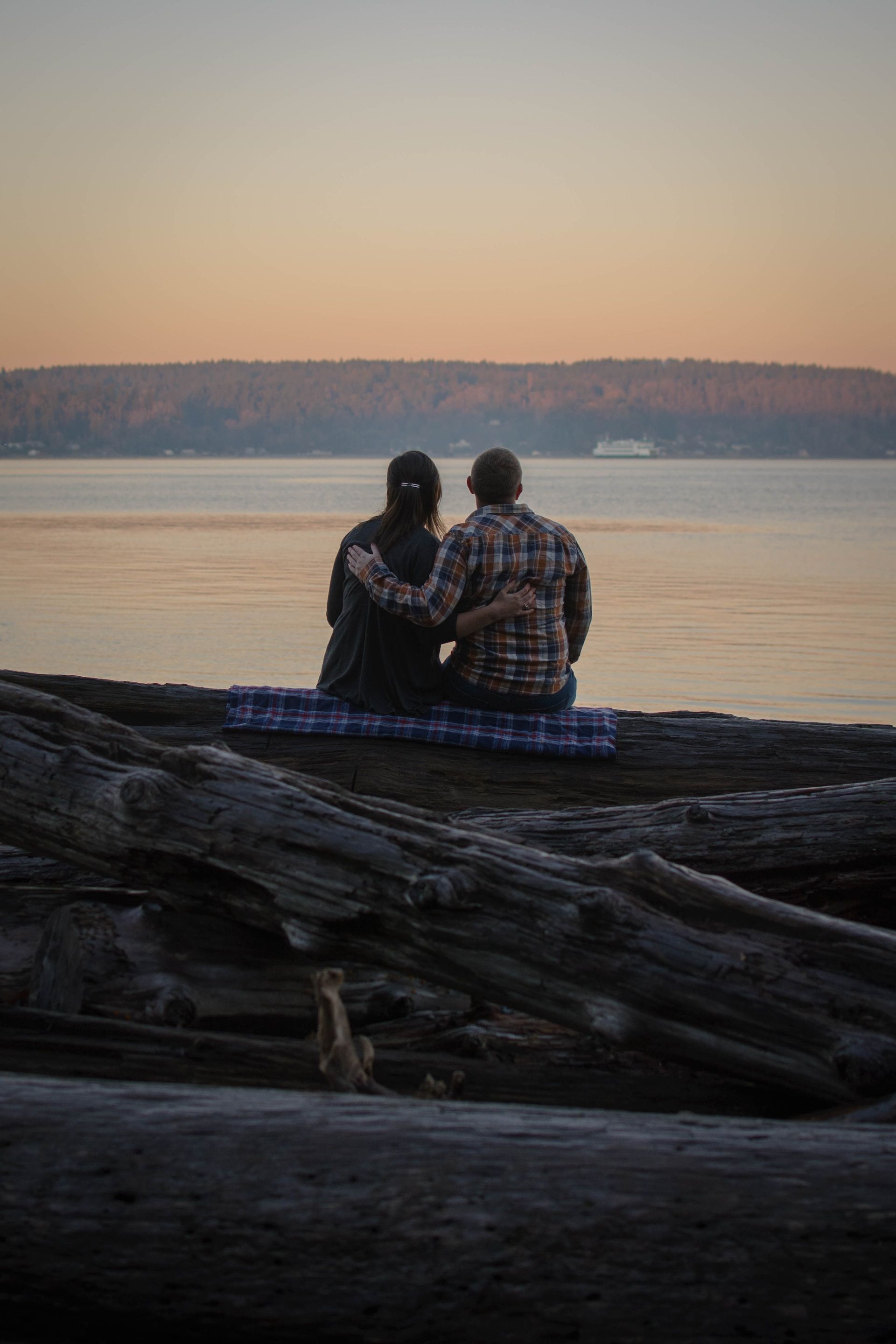 Two people sitting on driftwood at Owen Beach Tacoma WA
