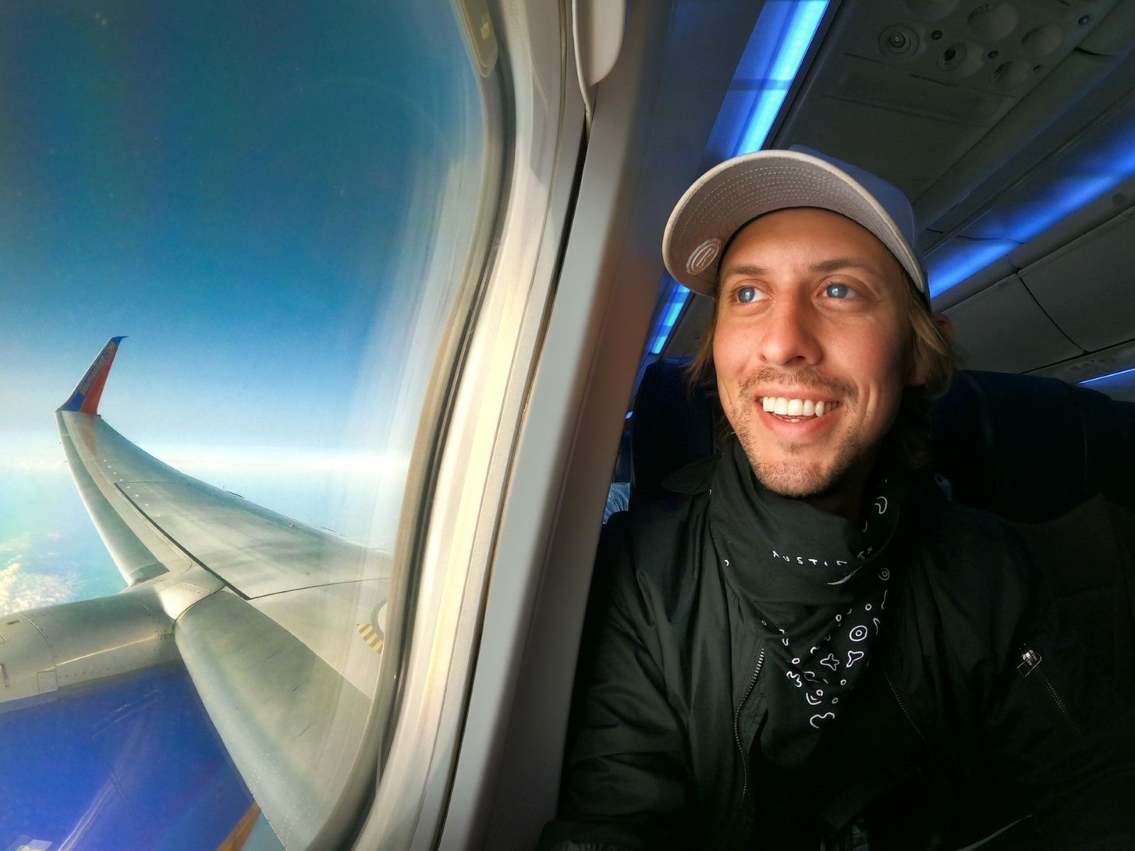 A young male traveler enjoying the view of the sky from an airplane window