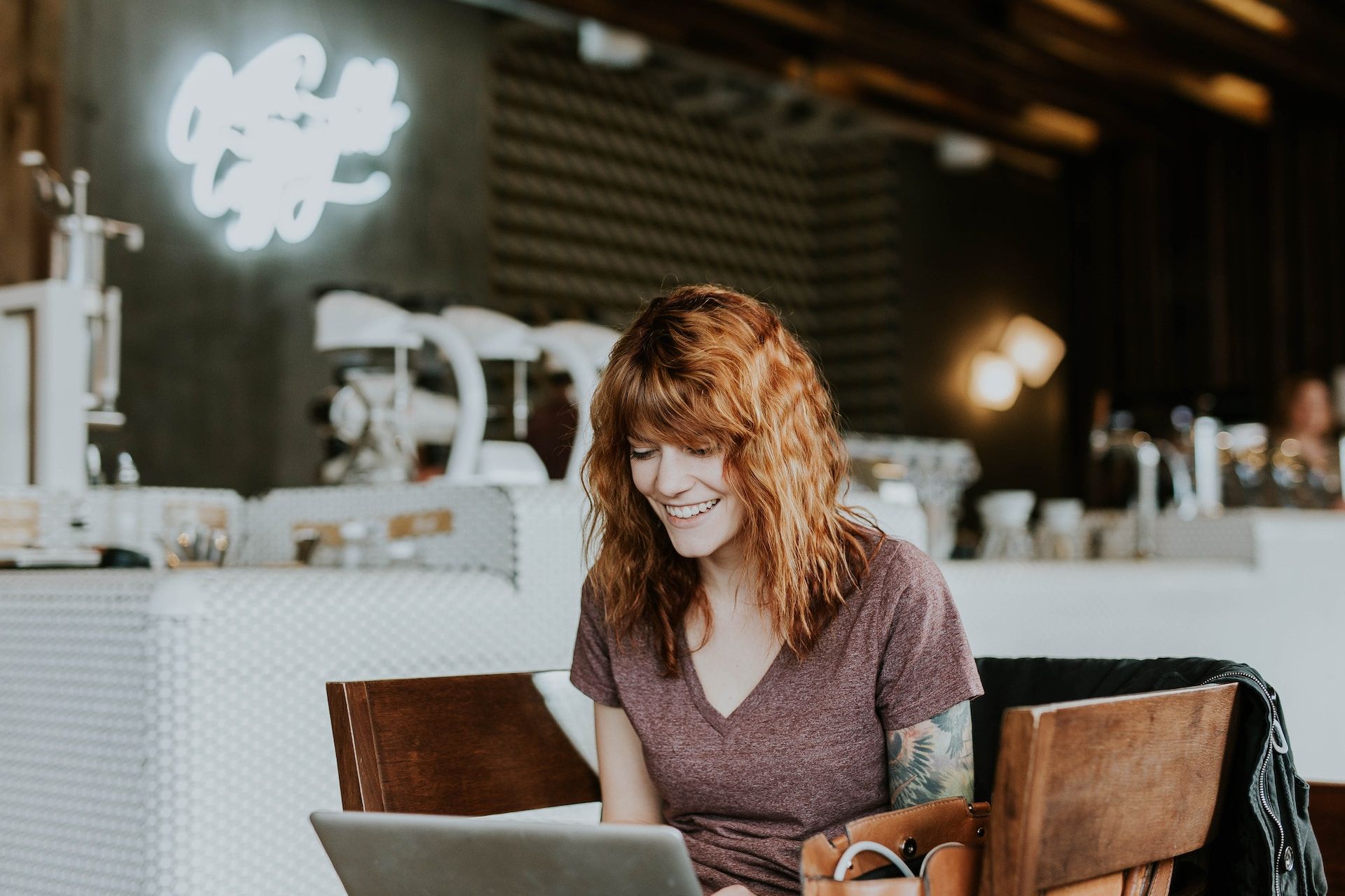     A woman sits on a brown wooden chair while using a laptop in Bentonville, USA 