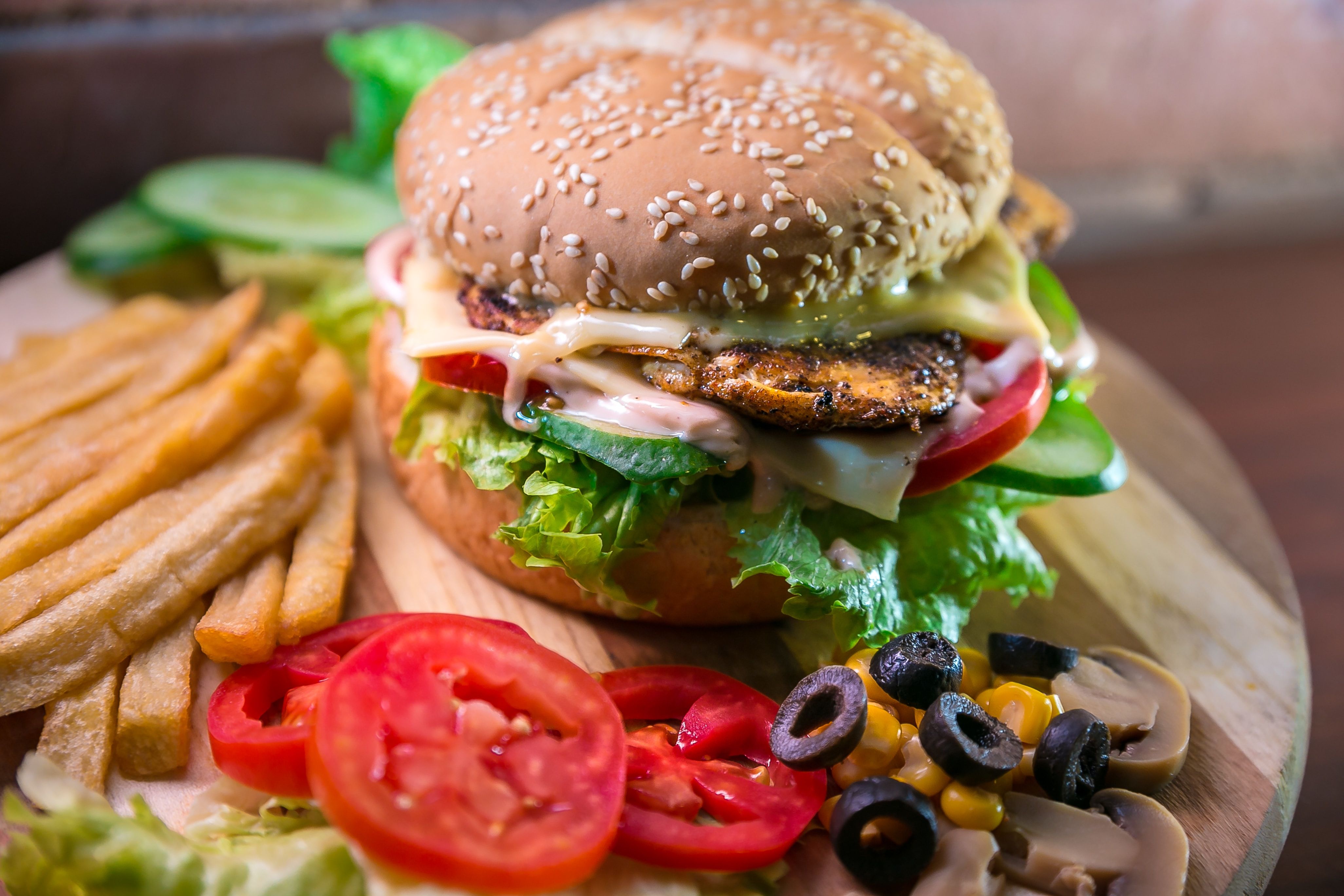 Burger on a table along with olives and other ingredients