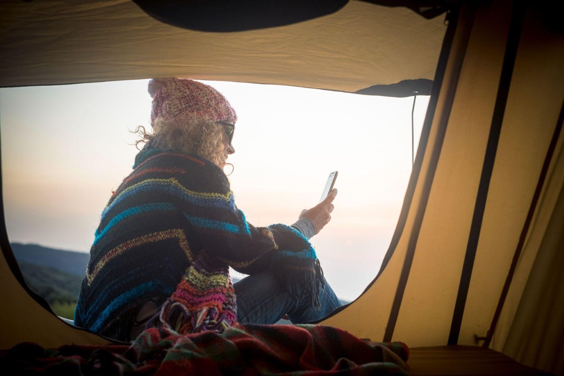 A female traveler using her phone while camping