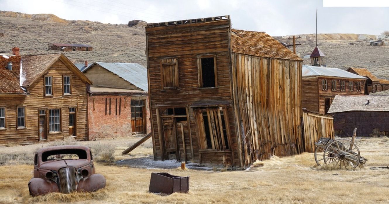 Rusty vintage car and old wooden houses decay in the American wilderness after the gold rush in the ghost town of Bodie, California, USA