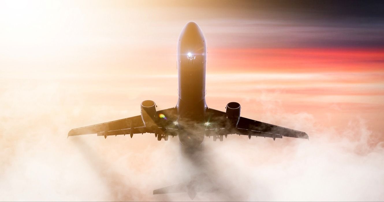 An airplane flying through fog, mist, and clouds against a sunset or sunrise sky at Hannover Airport, Germany