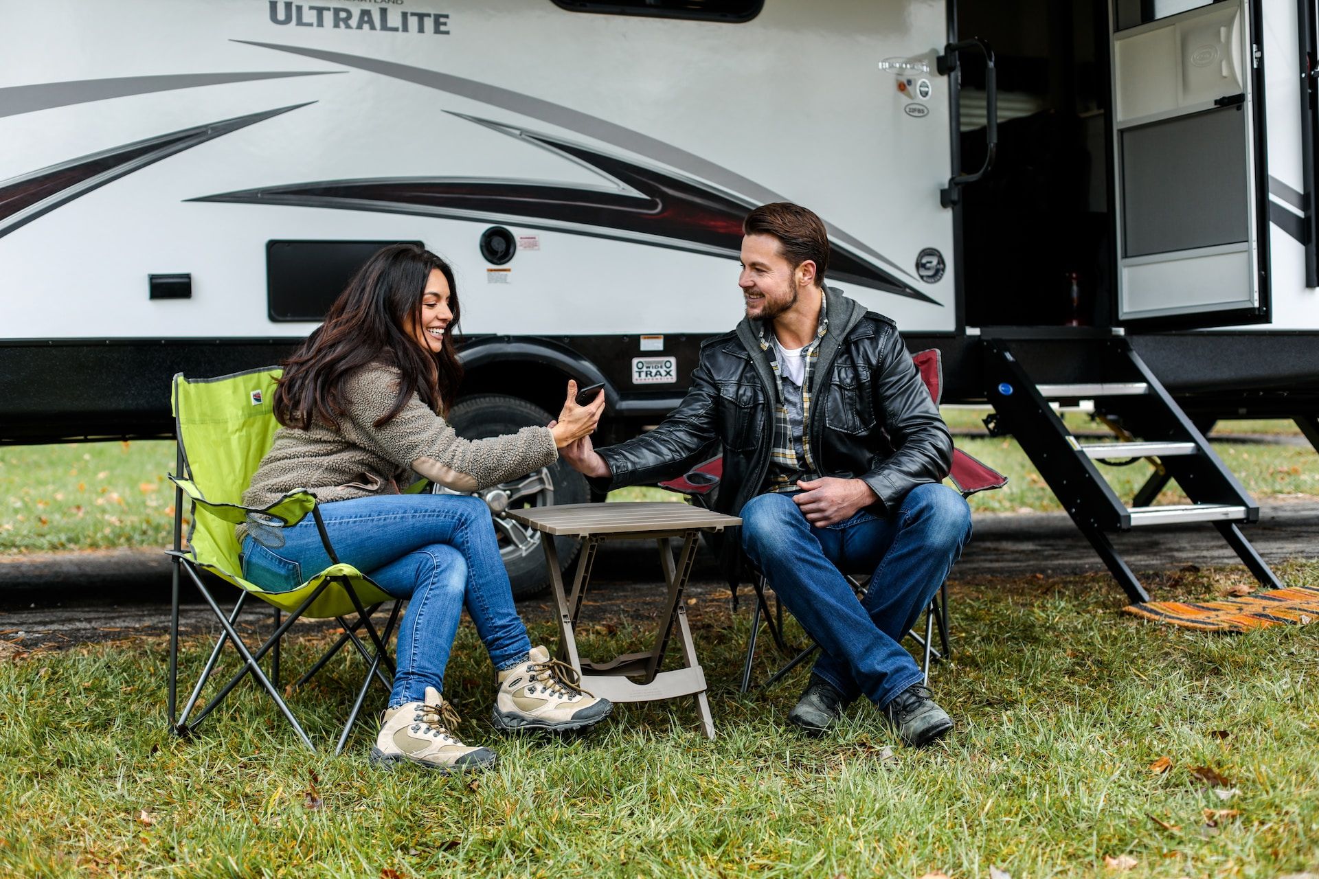 Two People Seated On A Chair Next To An RV