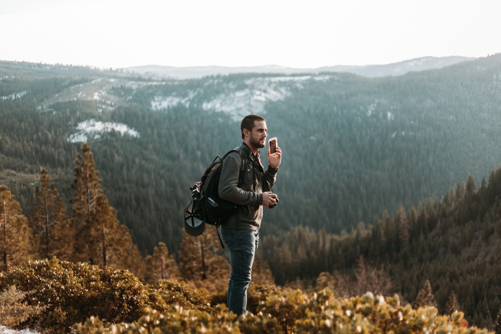 A male traveler standing on a mountain making a call