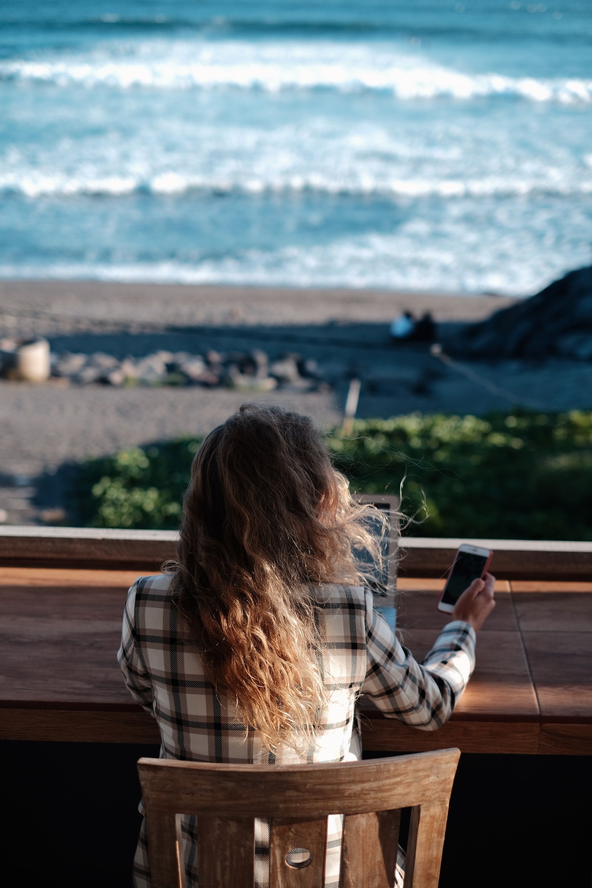Woman working on her laptop and phone while enjoying a stunning beach view