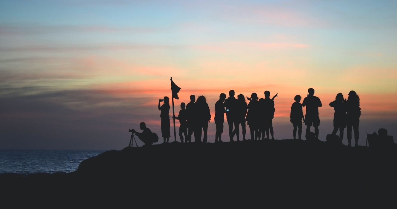Group of people silhouetted on a hill near water in Tanah Lot Temple, Indonesia