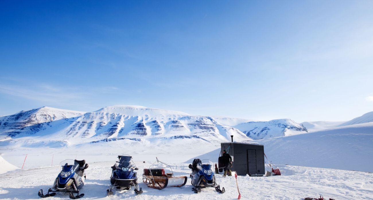 People preparing snowmobiles for an expedition in the Arctic