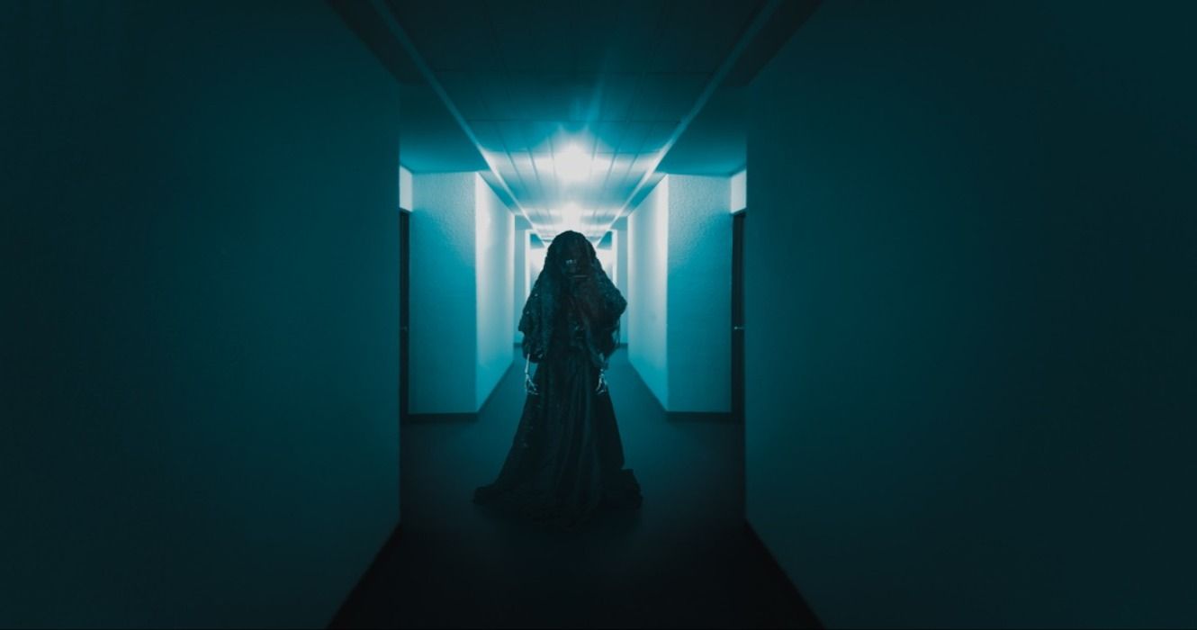 A ghost figure standing in a dark and creepy hotel corridor