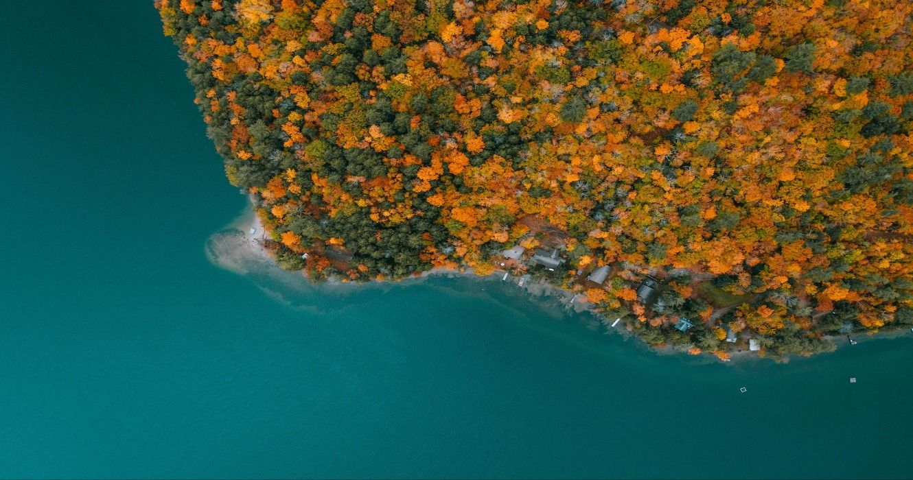 Aerial view of a blue lake surrounded by autumn fall foliage in New Hampshire, New England, USA