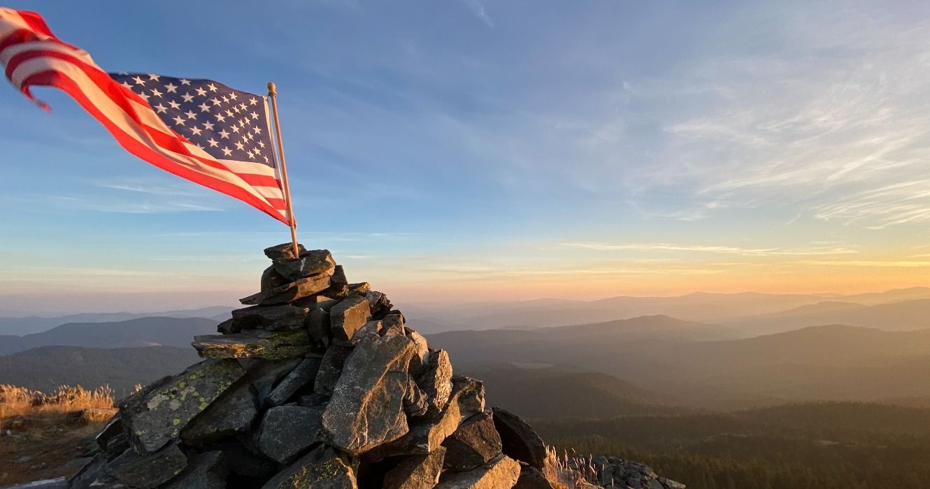 The American United States flag on top of a rock formation in Idaho Panhandle National Forest, Calder, USA