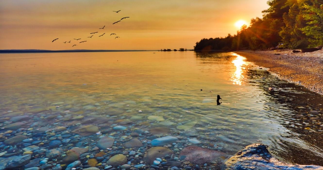 A view of a rock hunting beach along Lake Michigan at sunrise or sunset, taken between Petoskey and Charlevoix, Michigan, USA