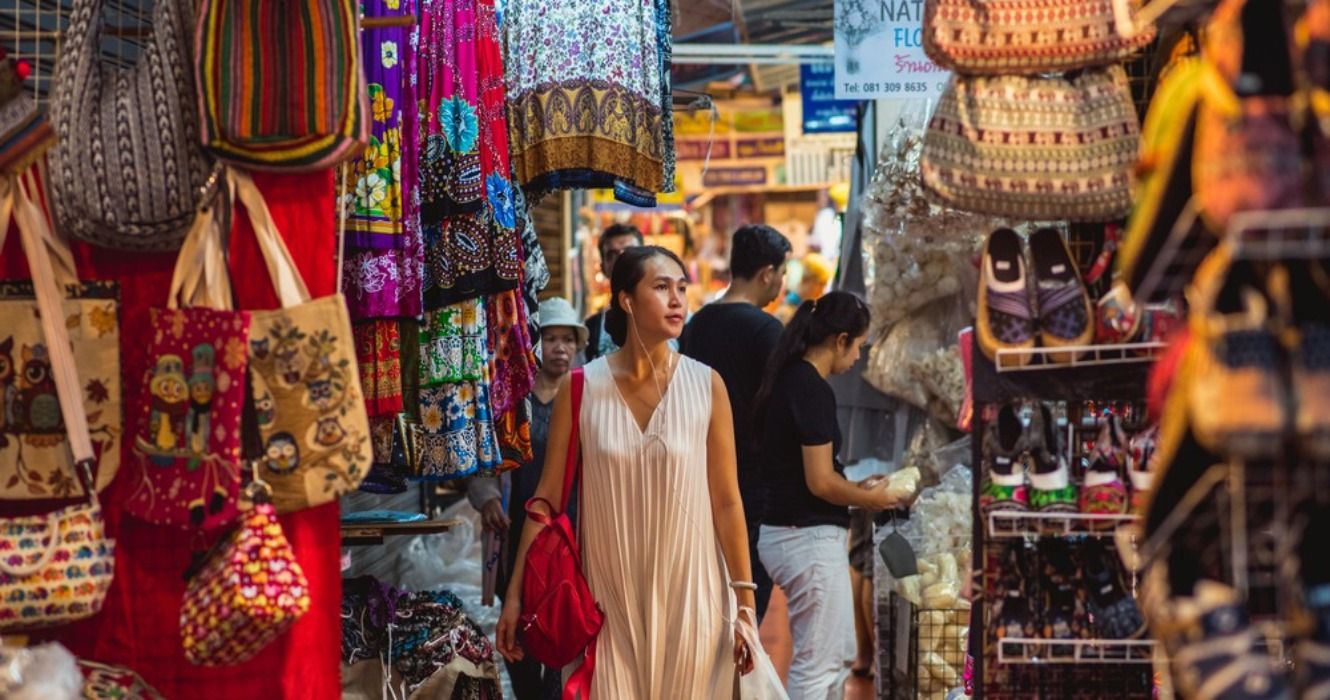 A woman walking through Chatuchak Market stalls in Bangkok, Thailand