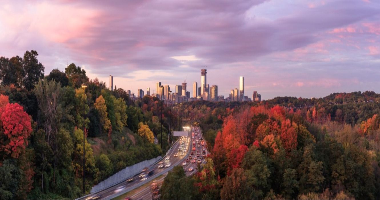 Cars approaching downtown Toronto on the Don Valley Parkway at sunrise, surrounded by fall foliage in the autumn in Toronto, Ontario, Canada