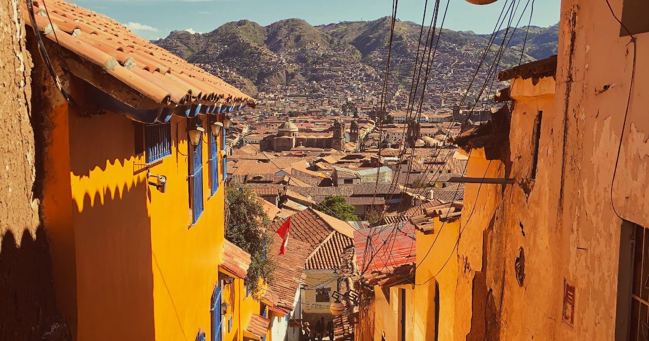 An alley amid the colorful streets of Cusco, Peru, with views of the surrounding mountains