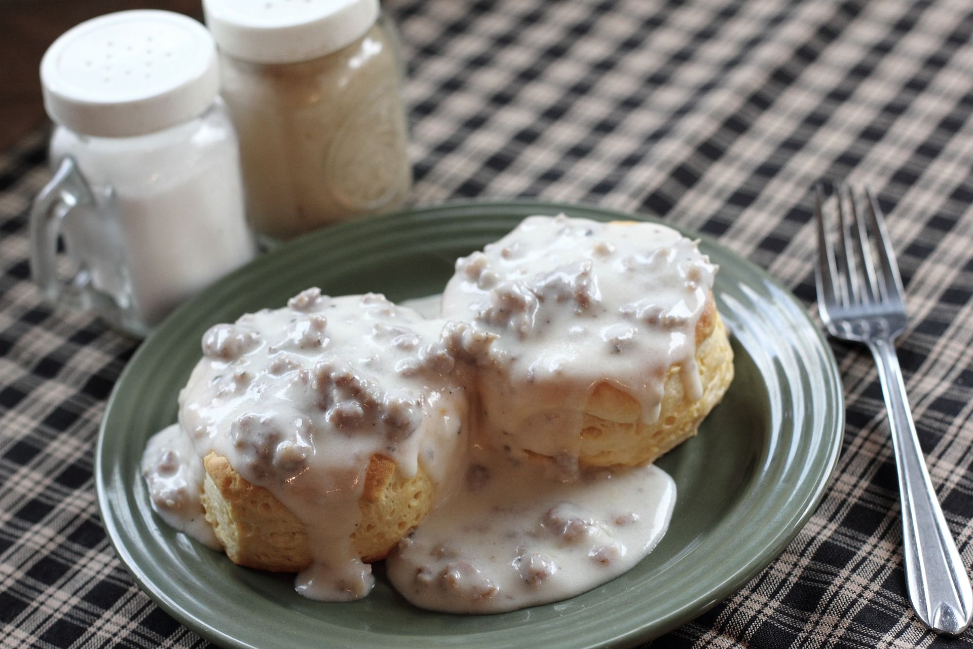 Plate of sausage gravy over biscuits on a table