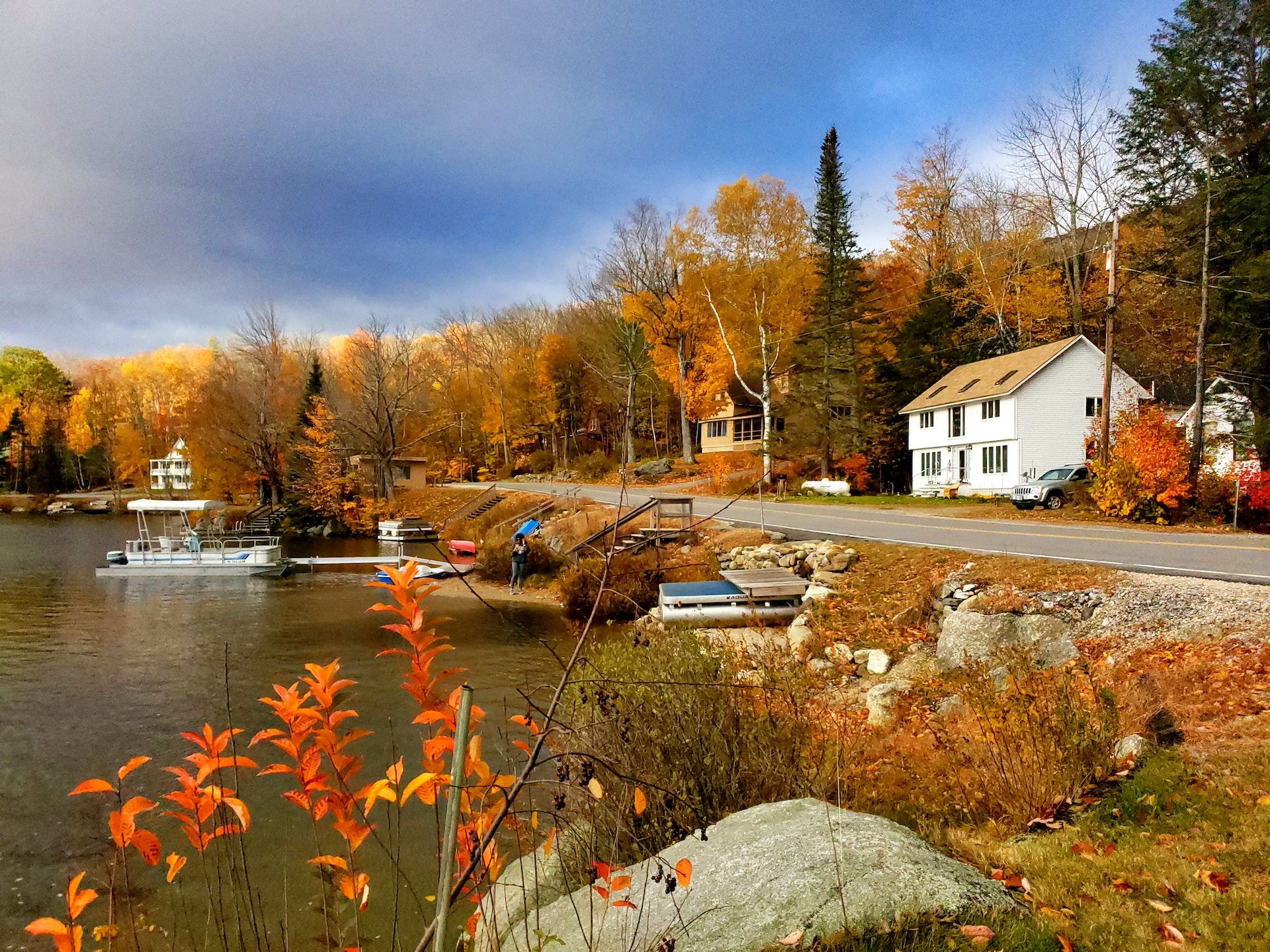 A white house sitting next to a lake in the fall New Hampshire. 