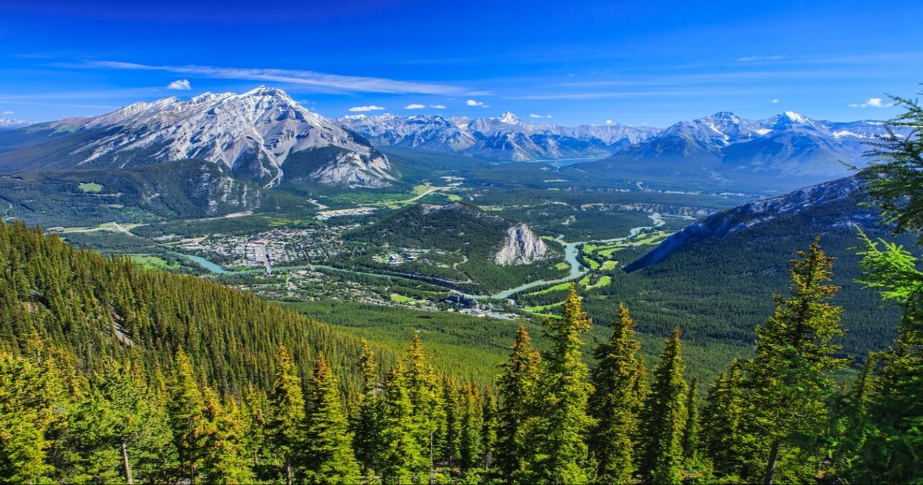 A view of forests, mountains, and the town of Banff in the valley of Banff National Park, Alberta, Canada