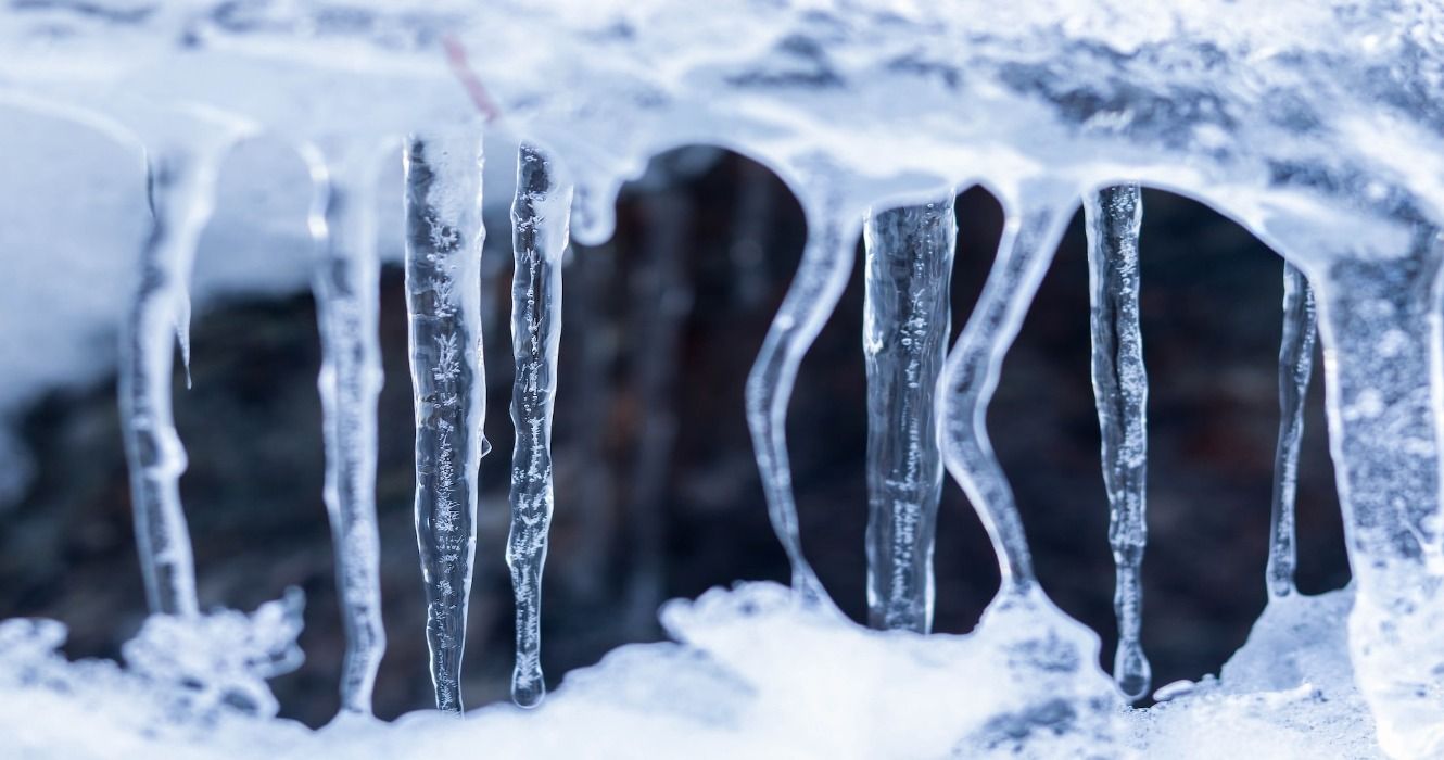 Icicles forming in the snow in the winter at a cave entrance