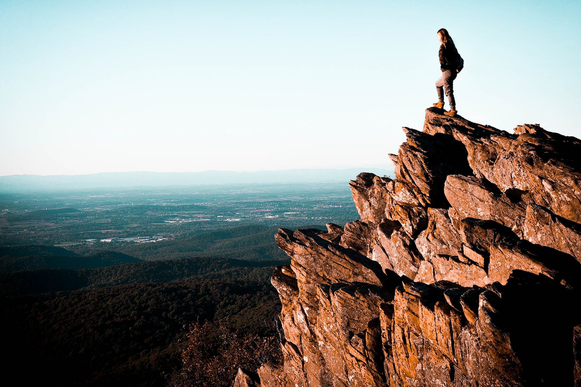 Hiker atop a rock formation admiring a Blue Ridge Mountains vista
