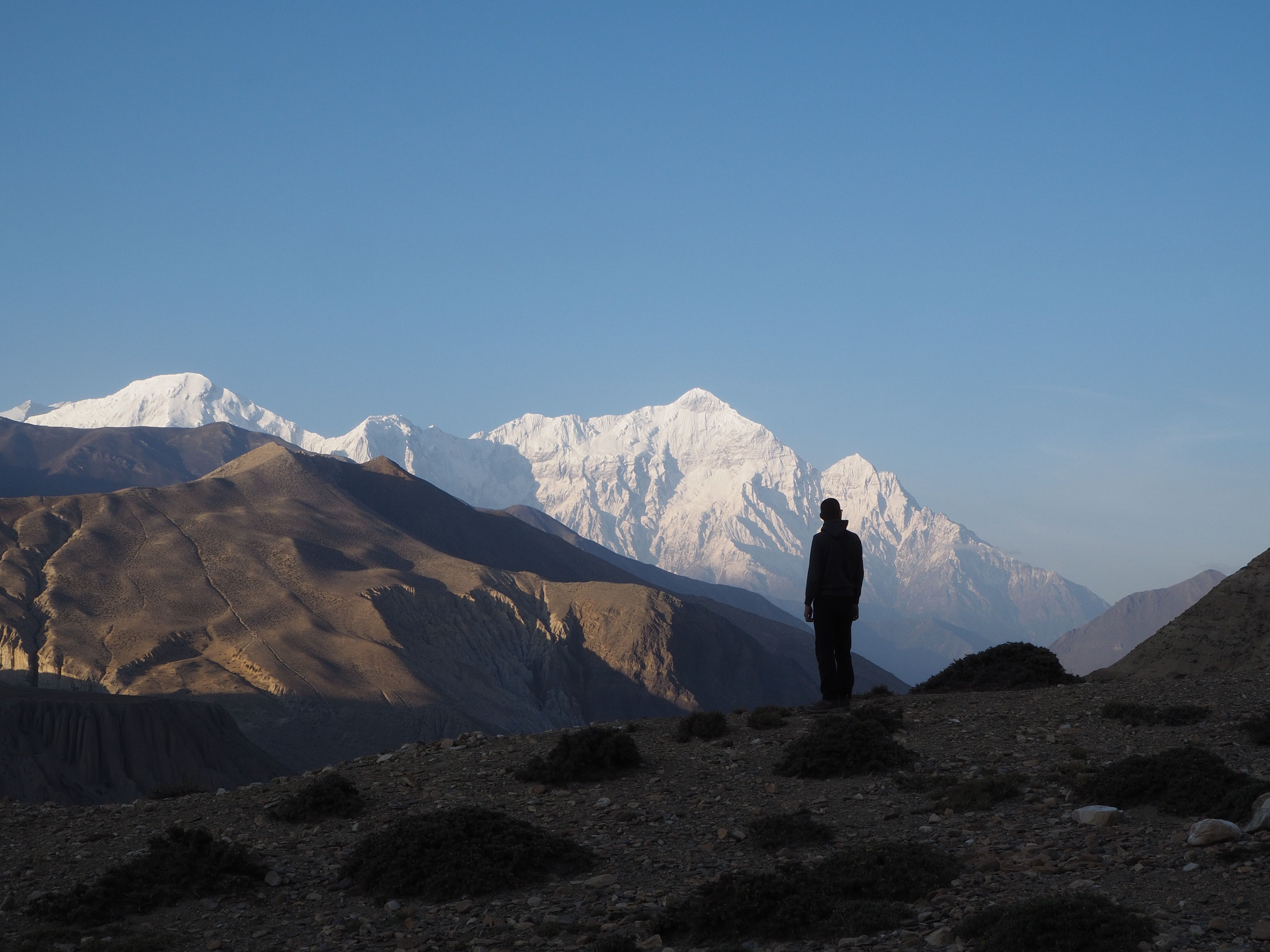 a man standing on top of a mountain with mountains in the background