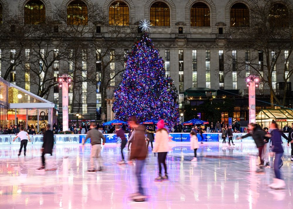 People ice skating in the Bryant Park rink with a Christmas tree in the background, New York City