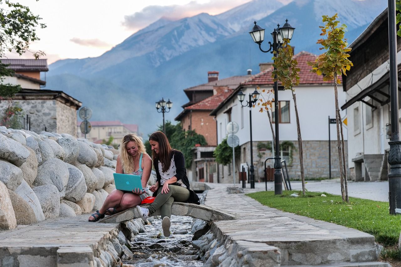 Two digital nomads sitting in the center of Bansko against the backdrop of Bulgaria's Pirin Mountains