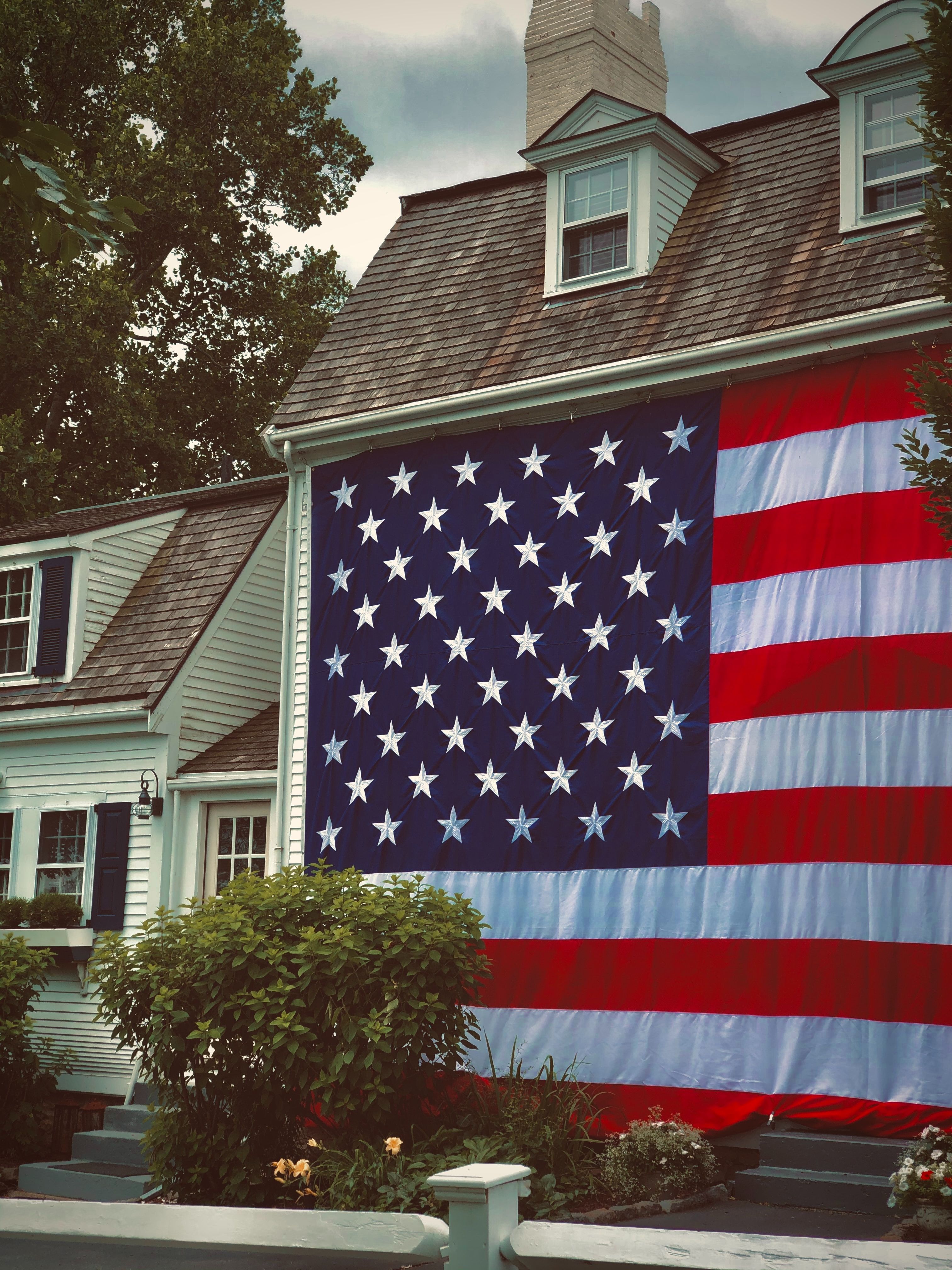 A giant American flag adorns the front of a beautiful old colonial home in Plymouth, Massachusetts.