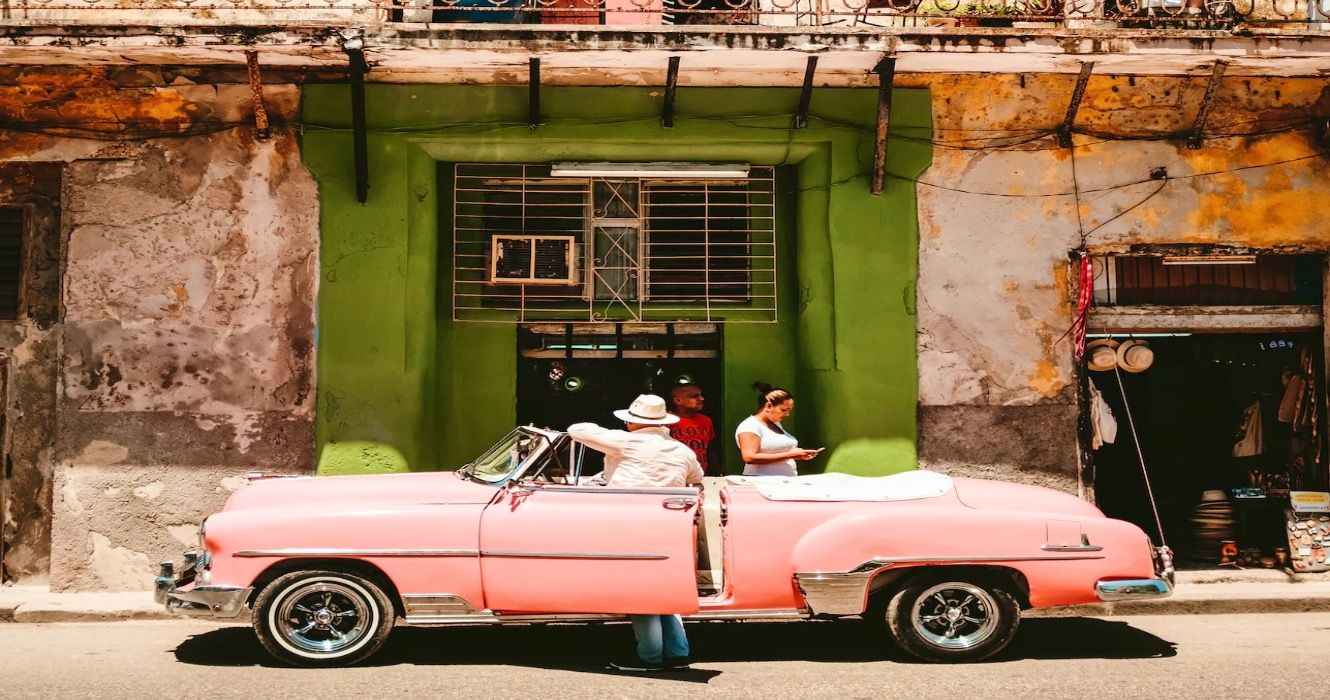 A pink car parked on the street in Cuba 