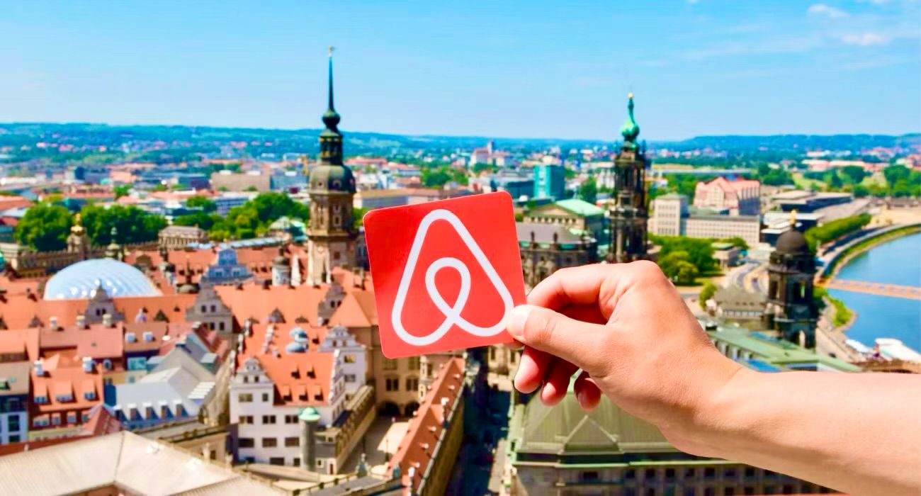 Man holding Airbnb logo over city