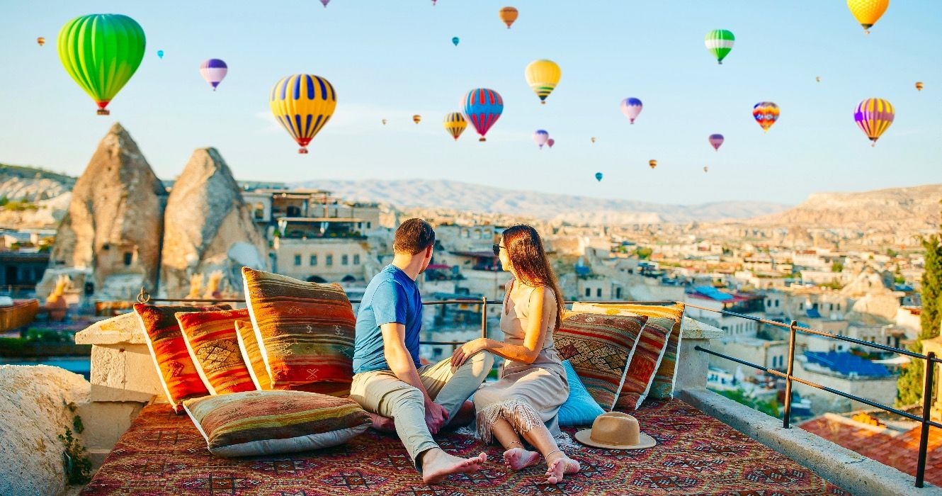 Happy young couple during sunrise watching hot air balloons in Cappadocia, Turkey