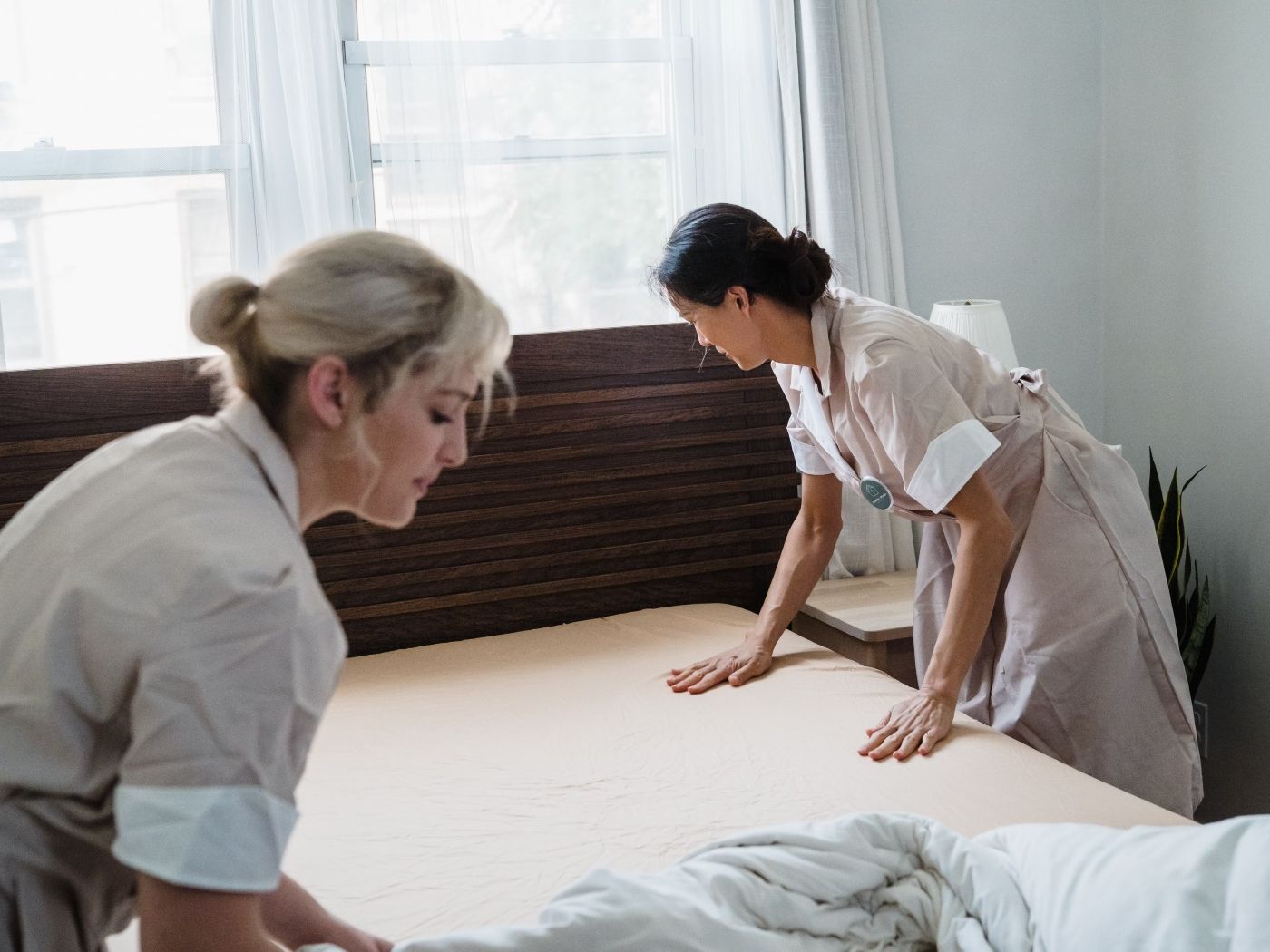 Hotel Staff Fixing the Sheets of a Bed 