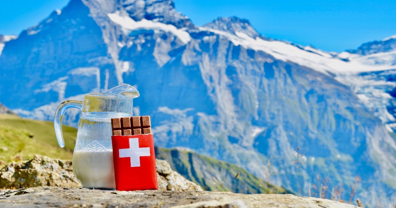Swiss chocolate and jug of milk against mountain peak. Switzerland