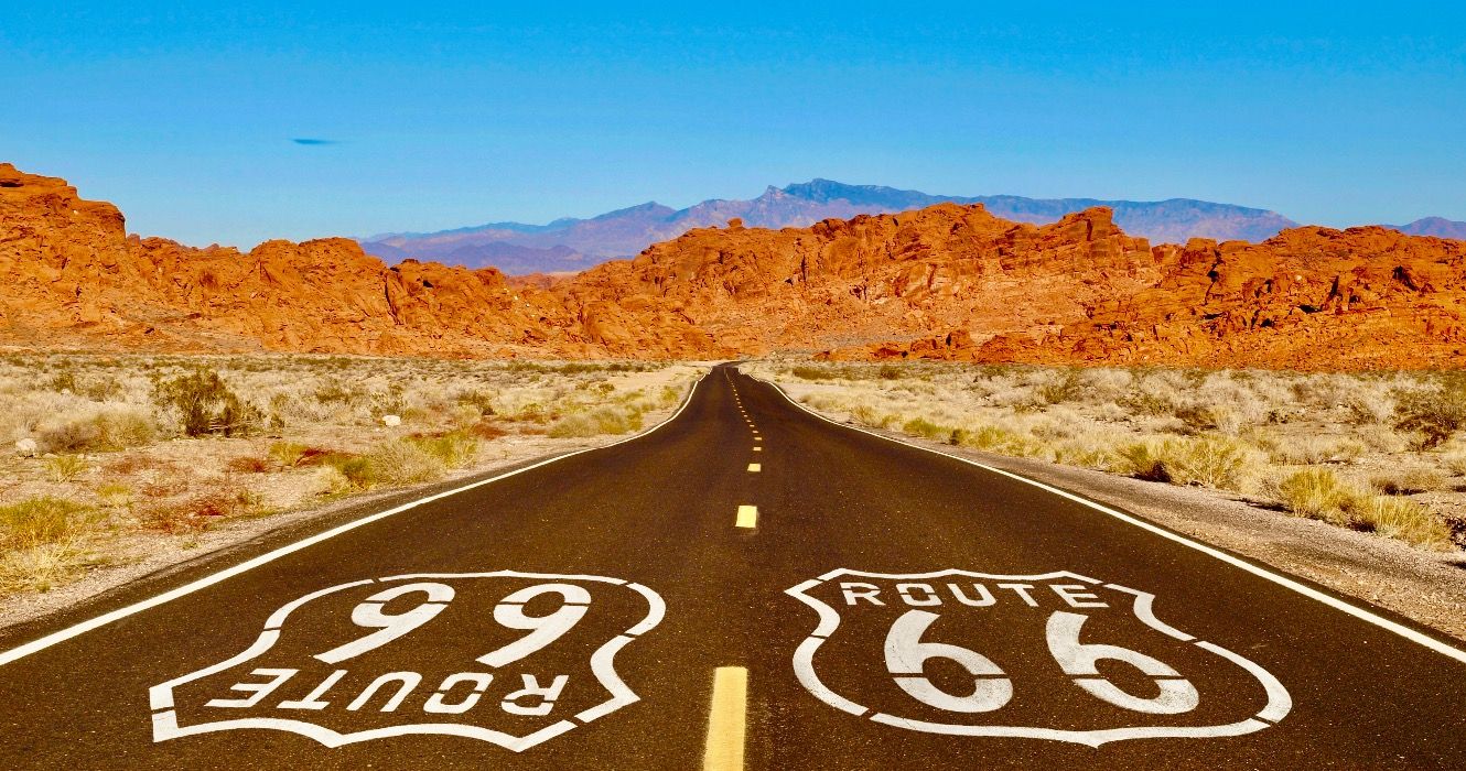 Route 66 pavement sign with Mojave desert red rock mountains