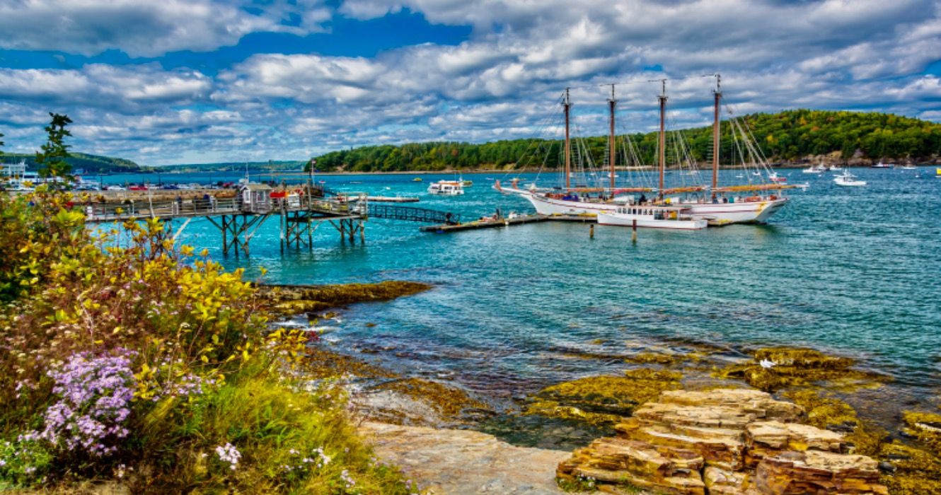 Rocky coast and view of boats in the harbor at Bar Harbor, Maine.