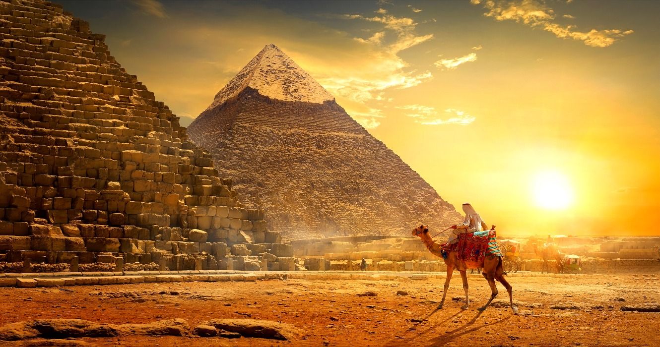 A man riding a camel in front of the Great Pyramids of Giza, Ancient Egypt