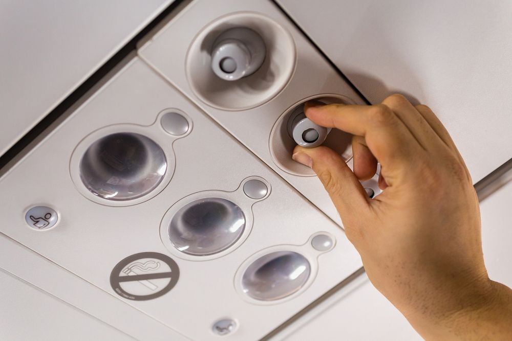 Hand adjusting an air vent on an airplane