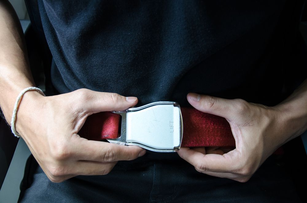 A person's hands on an airplane seat belt buckle