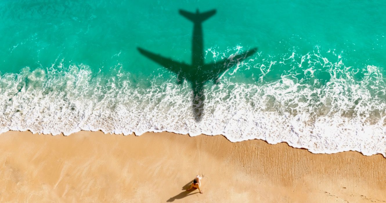 Airplane shadow flying over beautiful exotic tropical beach