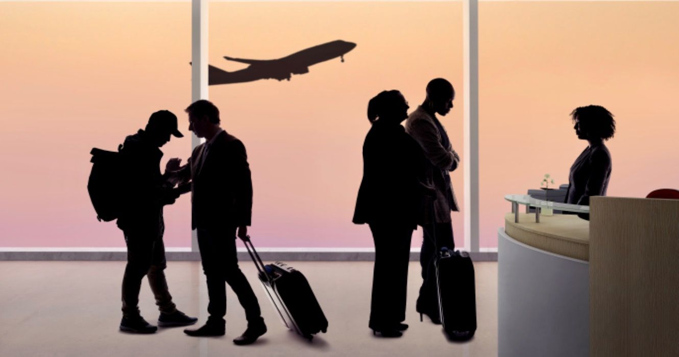 Silhouettes of passengers waiting in line at an airport check in counter