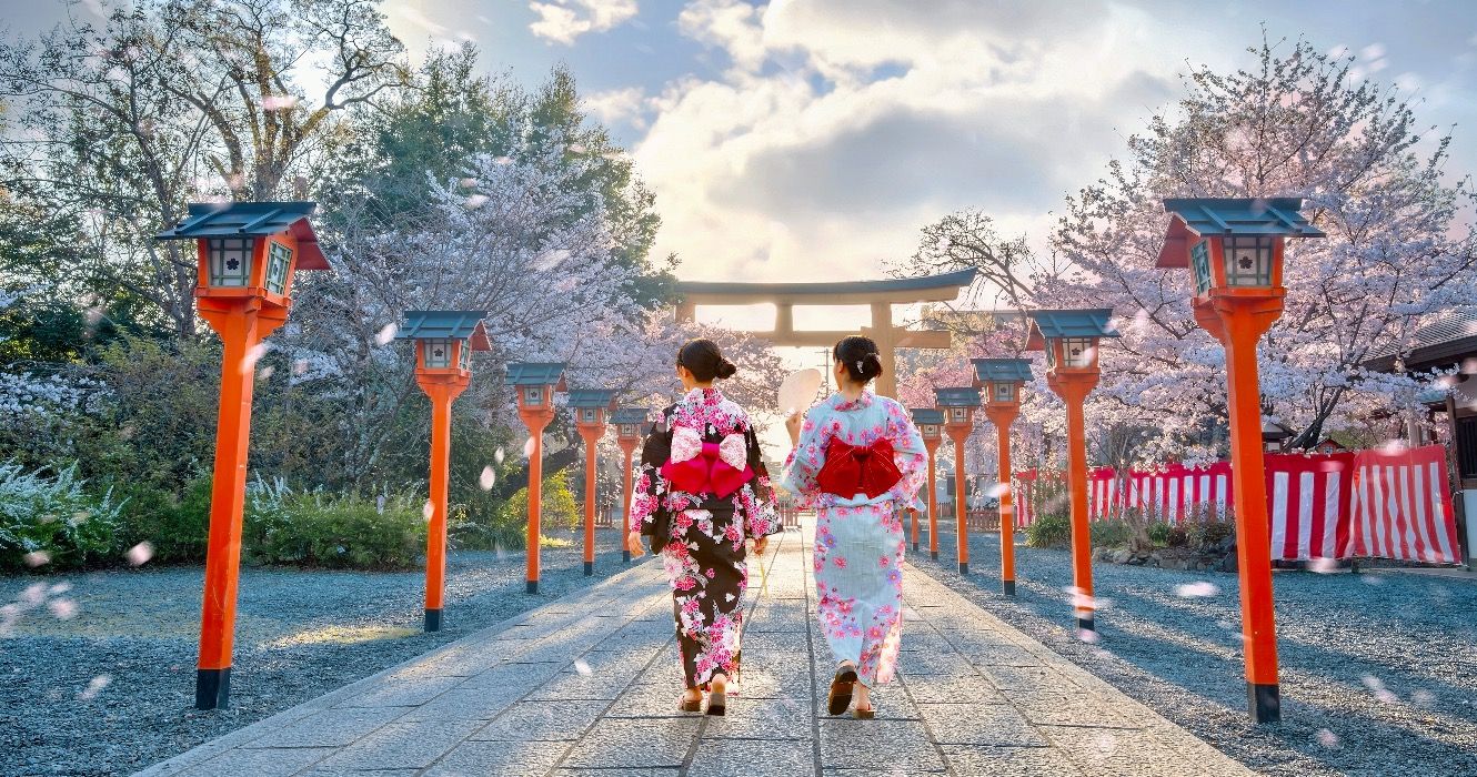 Young Japanese women in traditional Yukata dress stroll by Hirano-jinja Shrine in Kyoto, Japan