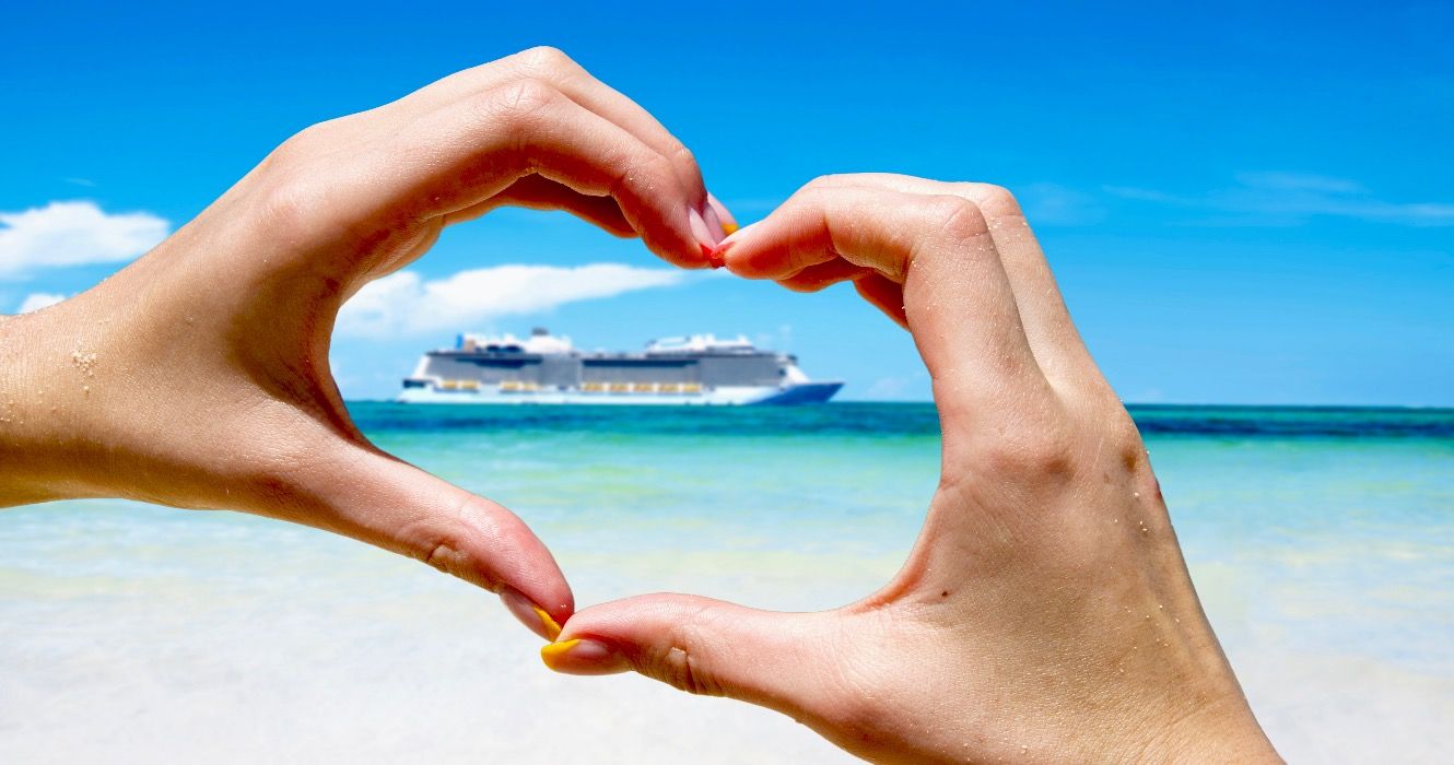 Cruise ship in the sea near the tropical island inside hands making a heart shape.