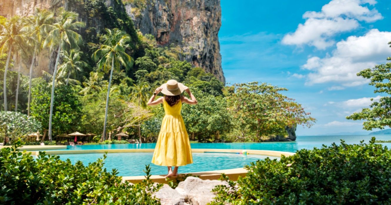 Woman tourist in yellow dress and hat traveling on Railay beach, Krabi, Thailand.