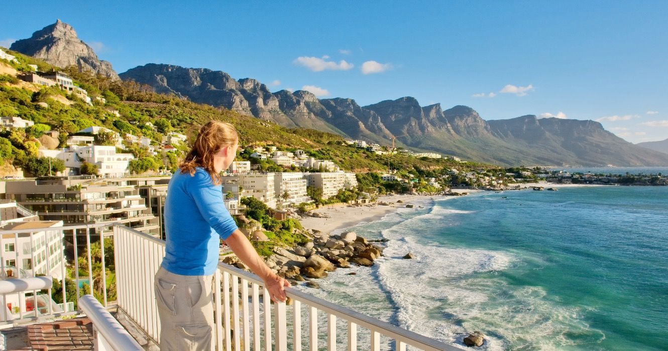 Young man on terrace looks at beach panorama. Shot in Cape Town, South Africa.